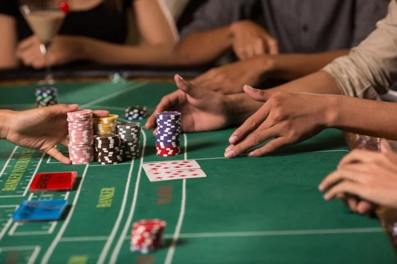 A close-up of a Baccarat table with cards and chips mid-play